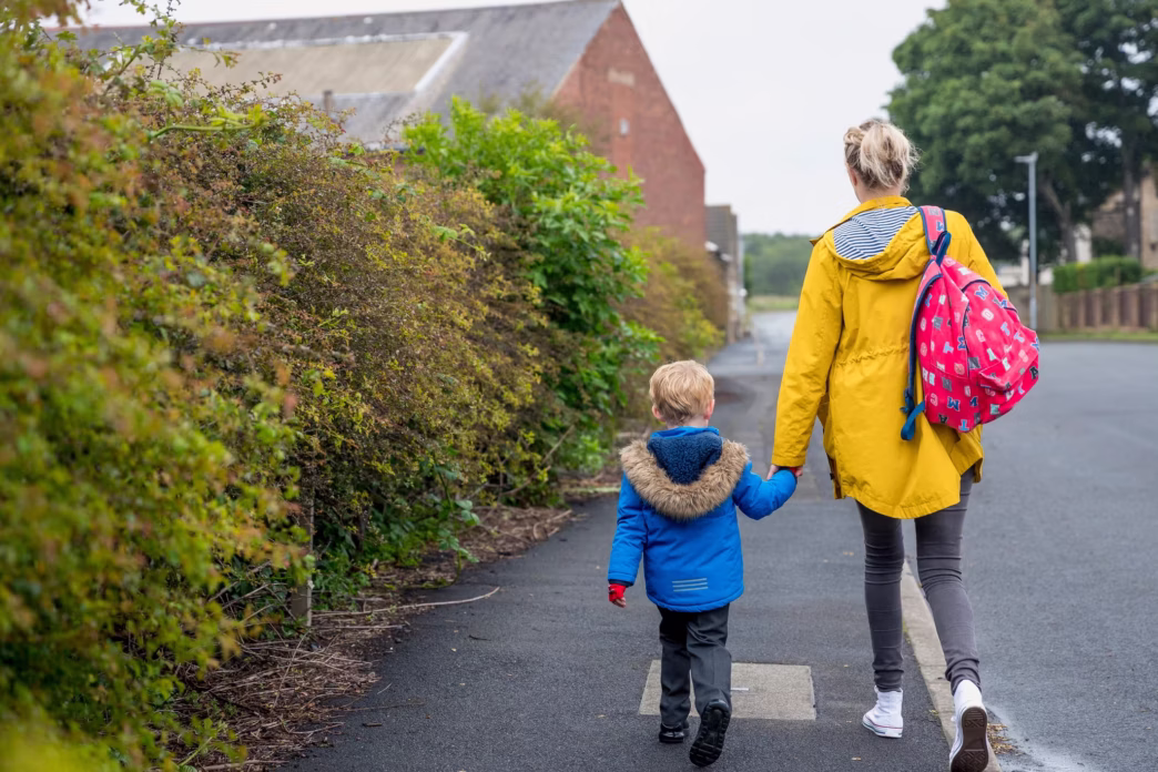 Mother and son holding hands walking to school