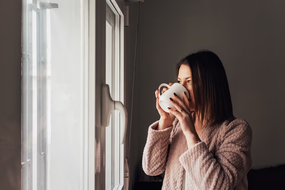 Woman drinking coffee looking out the window