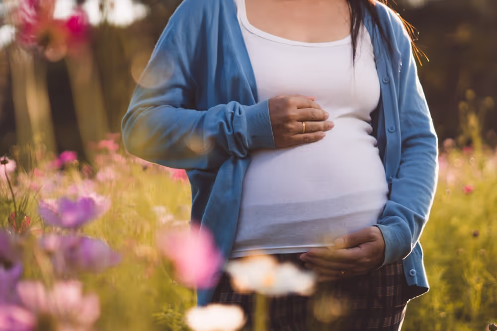 Pregnant lady in field holding her bump